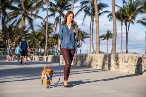 Red headed woman walking her puppy on a path in Miami